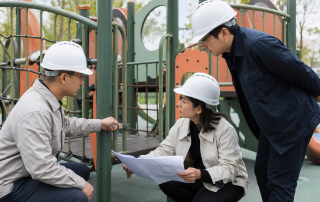采购、监理和技术人员在户外组合游乐设施旁核对图纸并检查构件间隙